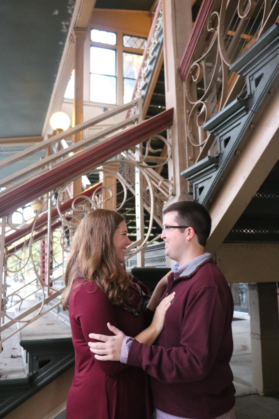 Haleigh and Sean looking into each other's eyes in front of a flight of ornate stairs
