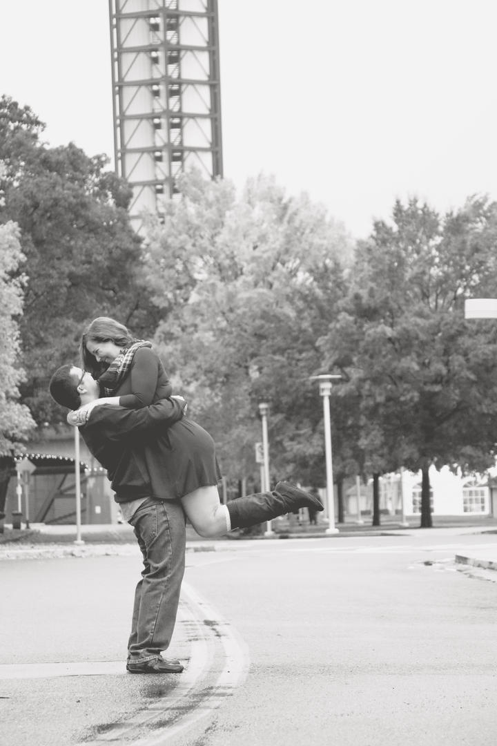 Black and white picture of Sean picking up and holding Haleigh in the middle of the road at World's Fair Park

