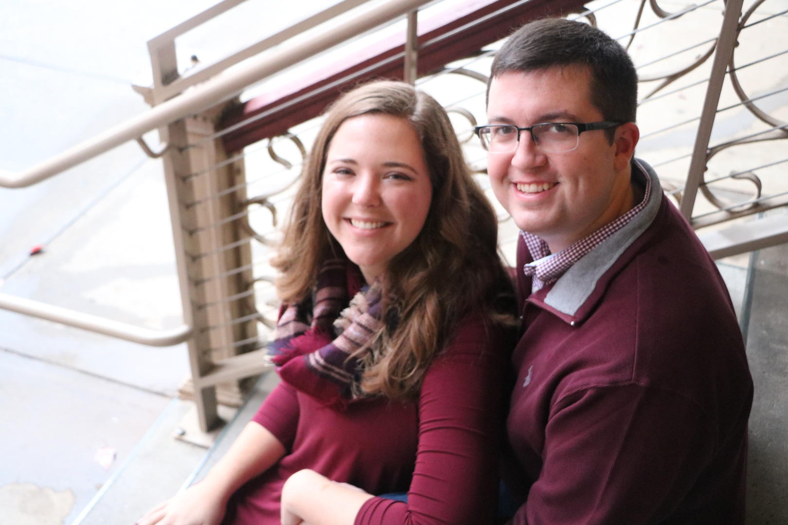 Haleigh and Sean looking back at the photographer while sitting on a flight of ornate stairs
